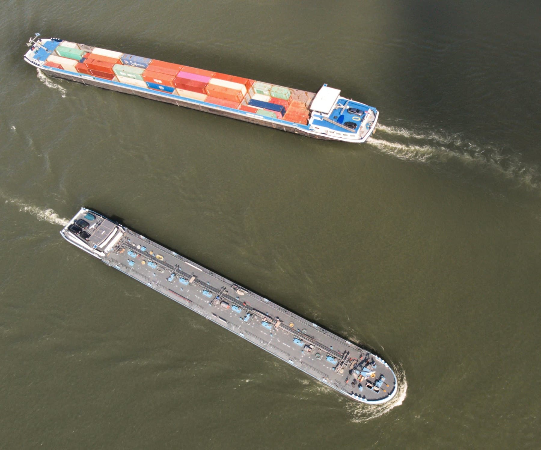 Two cargo barges passing on a wide river, seen from above