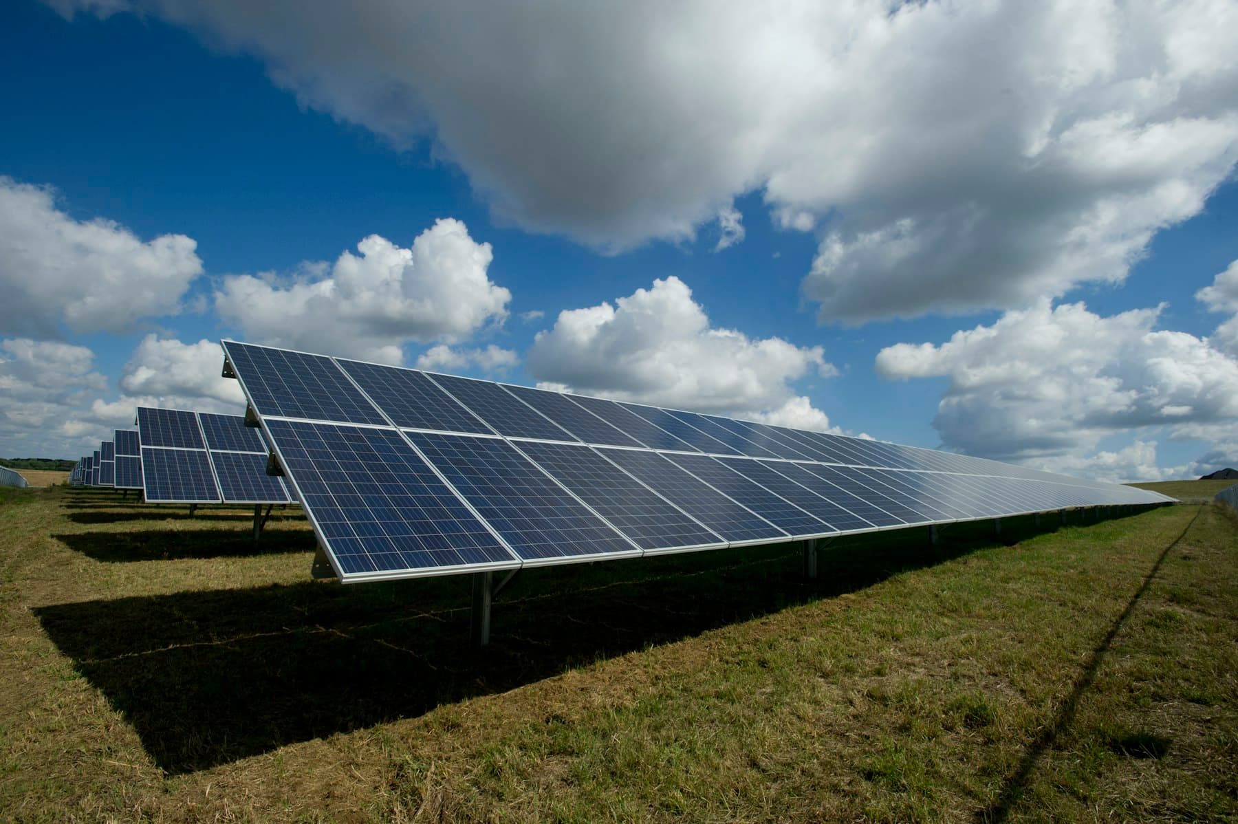 Solar panels in a grassy field under a cloudy sky
