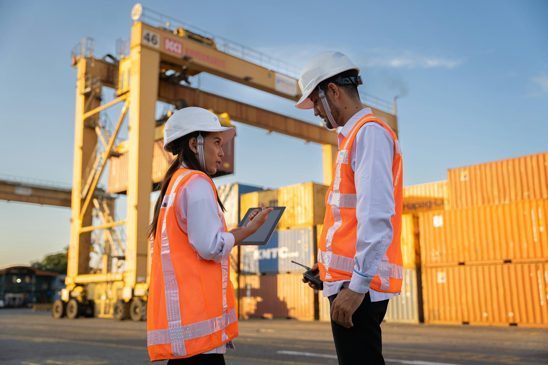 Port operations staff in hard hats reviewing plans beside containers