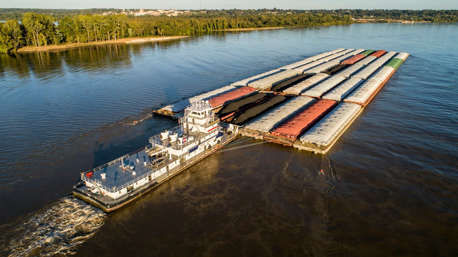 Pushboat moving a string of loaded barges along a river