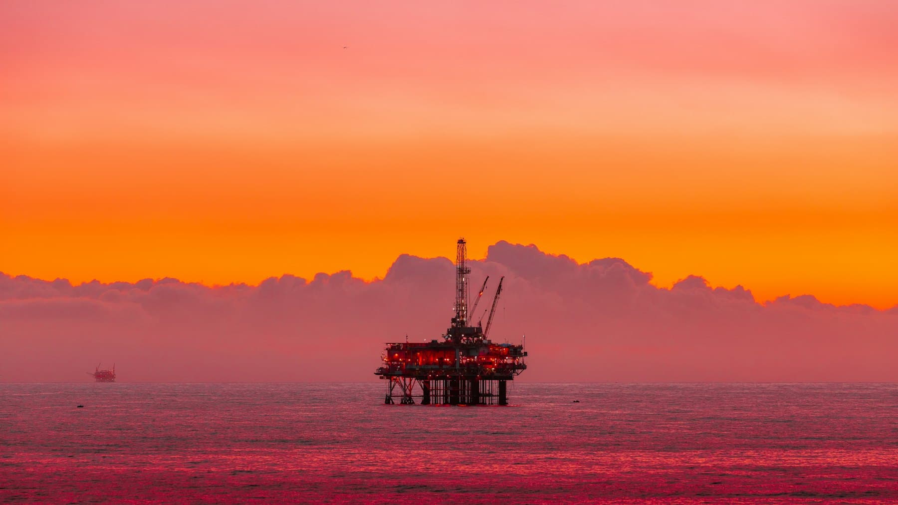 Offshore oil platform on the horizon at sunset