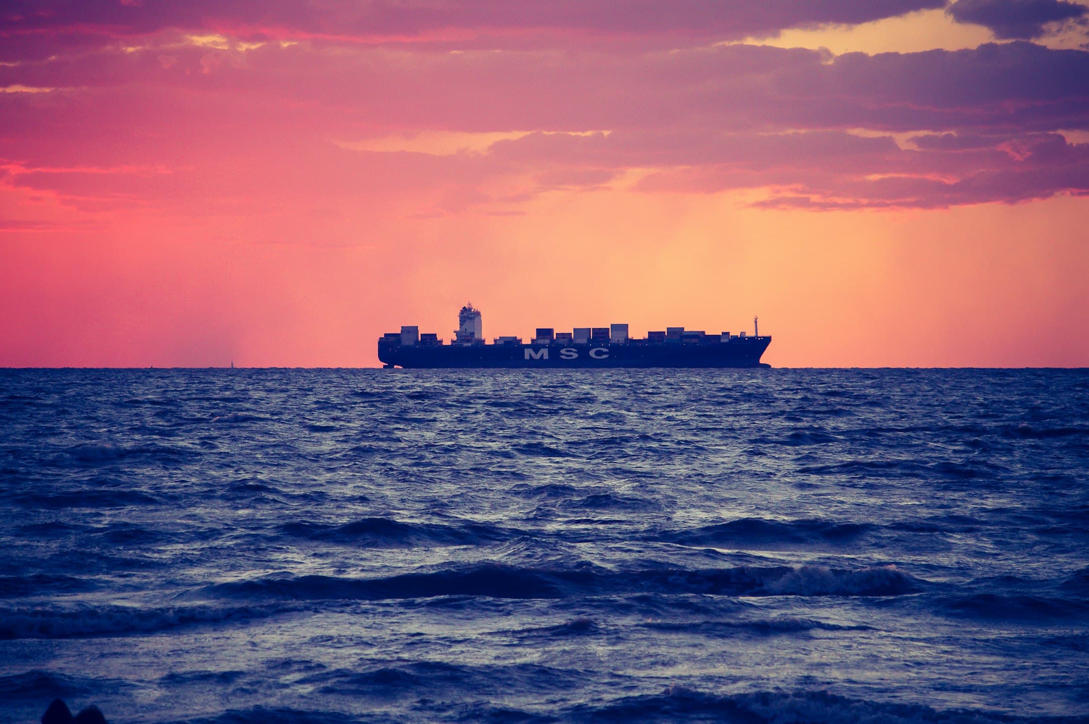 Container ship crossing open sea at dusk